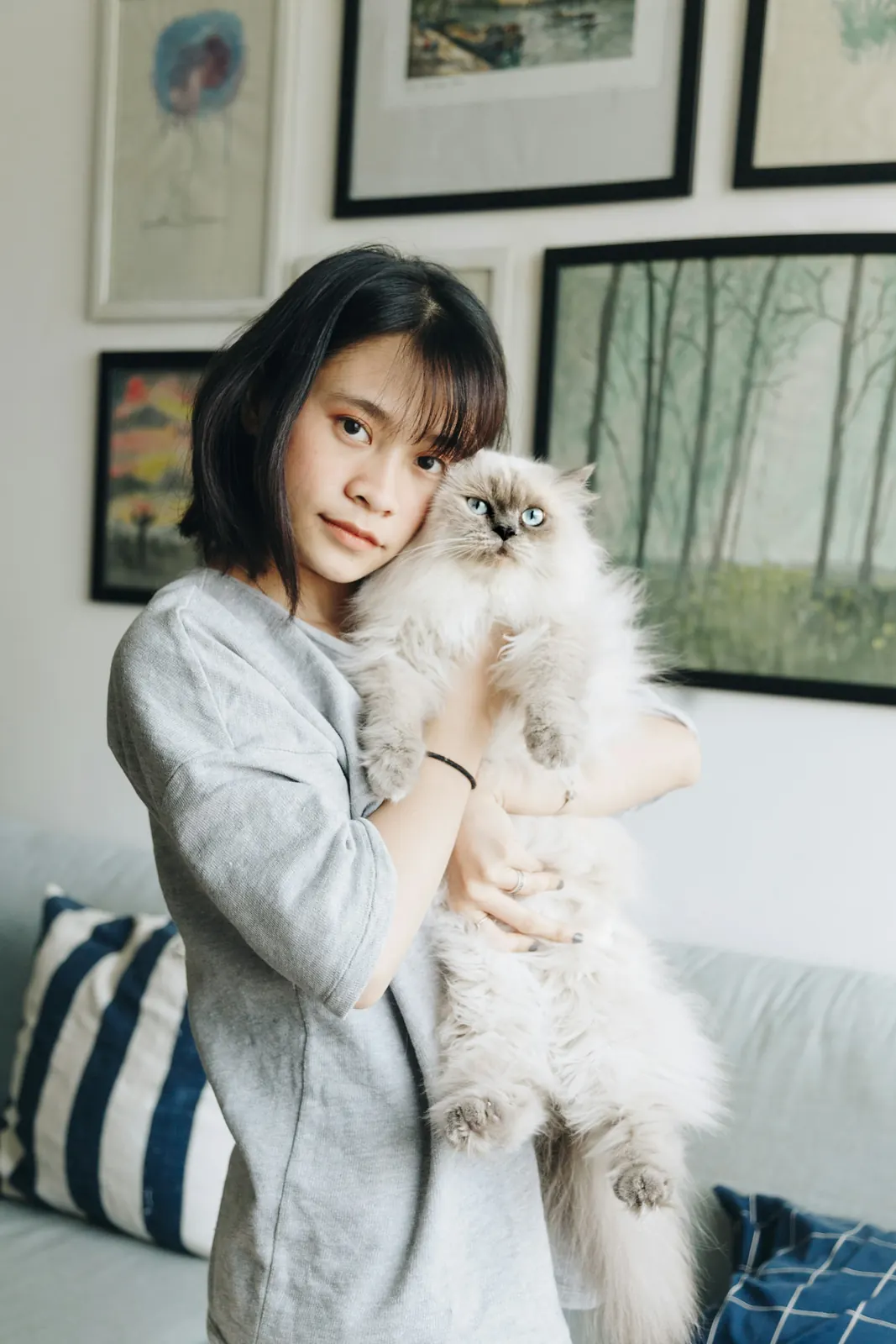 Woman holding her fluffy cream cat close at home